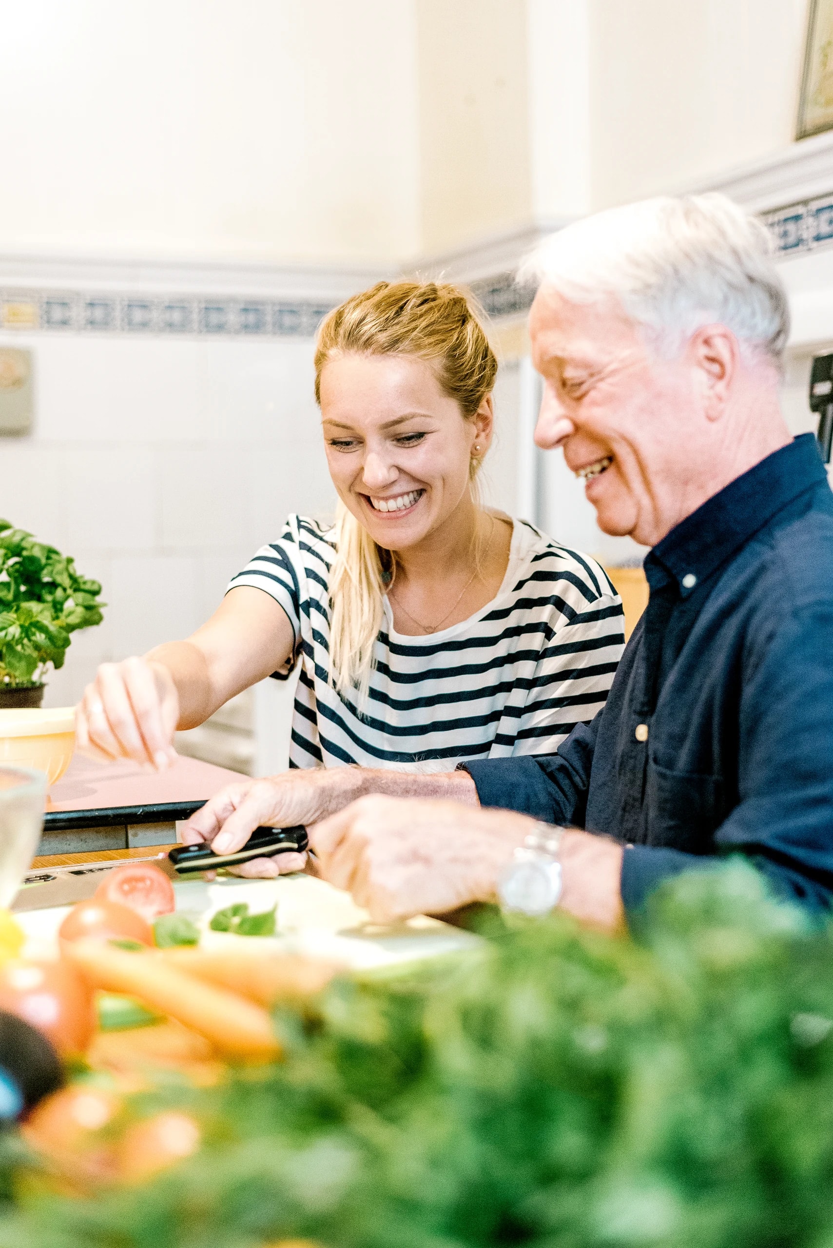 Eine Alltagshilfe bereitet gemeinsam mit einem Senior Gemüse zu